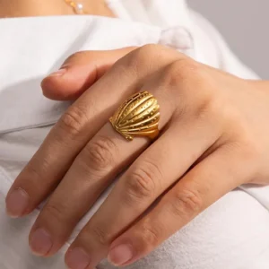 18K gold seashell ring worn on model's middle finger, realistic embossed shell with polished finish, styled with white linen shirt for everyday wear