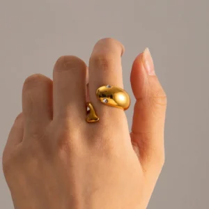 Gold serpent open ring worn on female hand close-up detail shot highlighting chunky gold band with split serpent ends and CZ stone