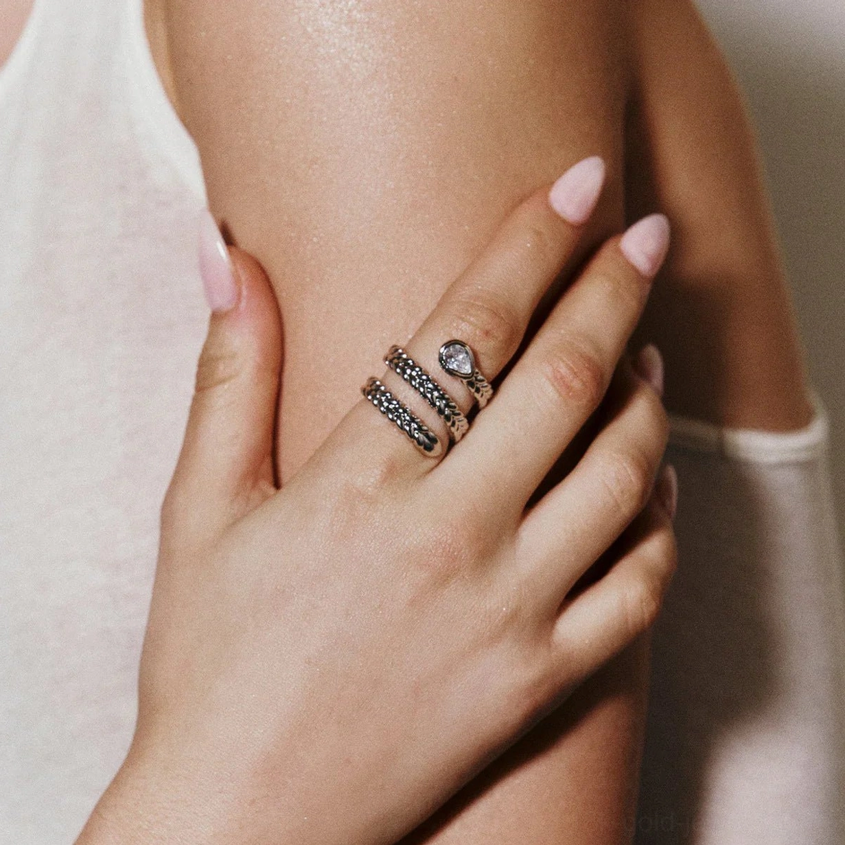 Stacked pave stone 18K gold serpent rings close-up on female hands light skin tone finger detail