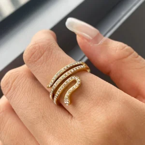 Close-up side view of 18K gold Serpentina ring worn on finger, showing sparkly crystal accents and gold wrap design