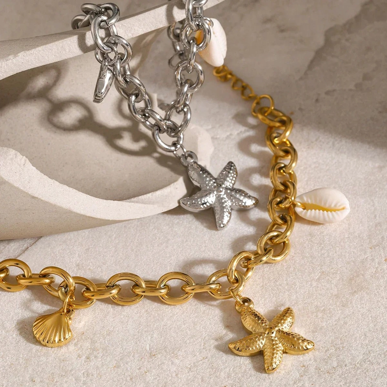 18k gold and silver ocean charm bracelets flat lay stone background twisted chain