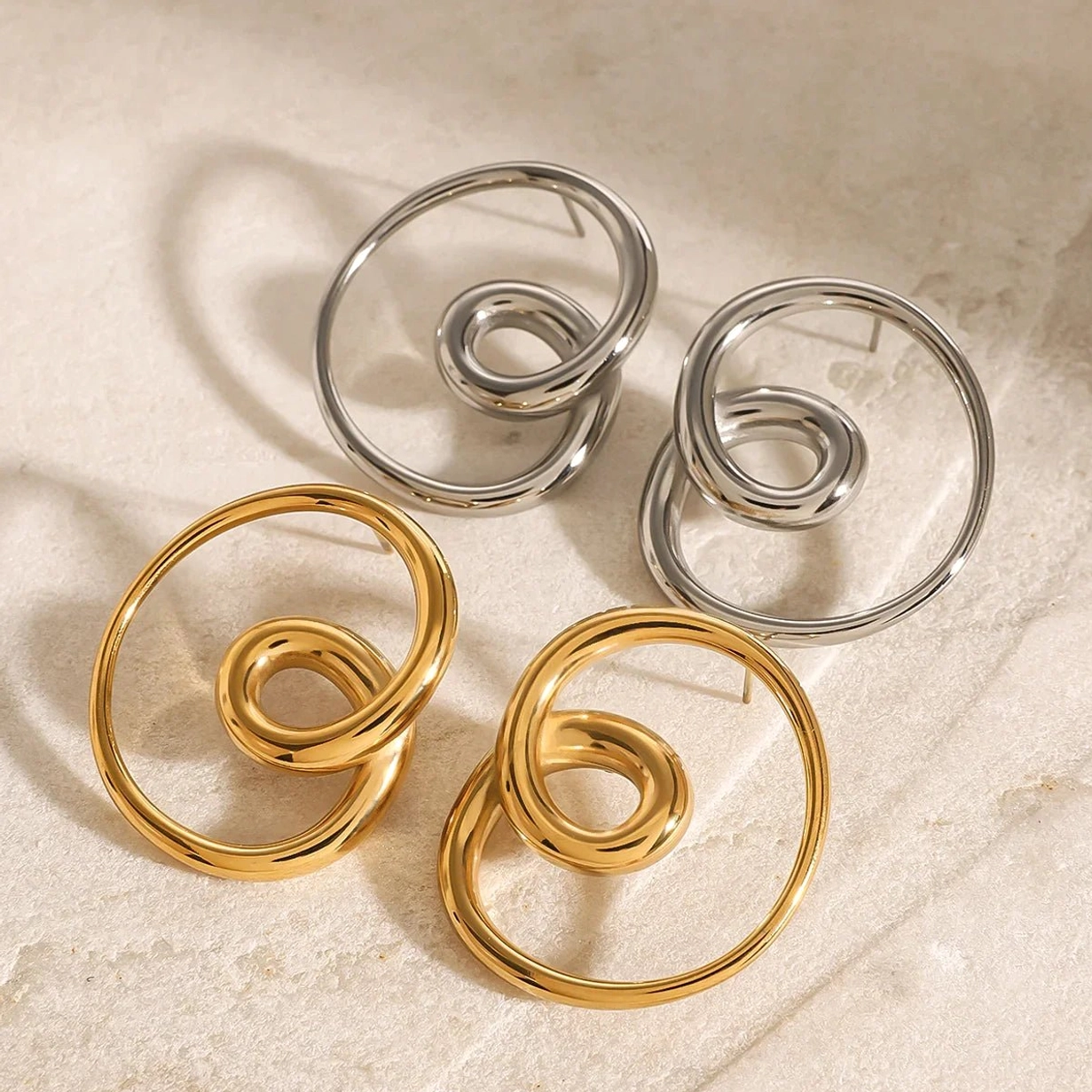 Gold and silver twisted spiral earrings both colors marble background top-down close view