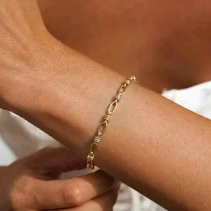 Two-tone mixed metal bracelet worn on delicate wrist close-up showing textured links and slim fit on ivory background