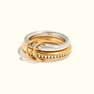 Two-tone 18K gold and silver stackable ring set with crystal pavé detailing, flat lay on beige background showcasing all three rings