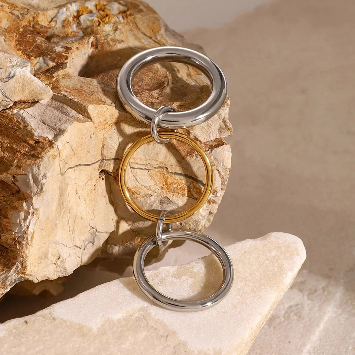 Vertical flat lay of 18K gold and silver two-tone stacked rings - polished smooth finish on natural stone background