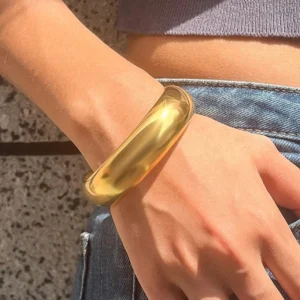 Gold smooth bangle bracelet worn on wrist with casual denim outfit side view styling