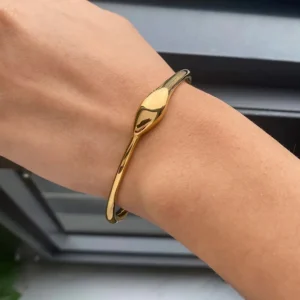18K gold snake bangle worn on light-skinned female wrist side view streamlined snake motif open cuff bracelet