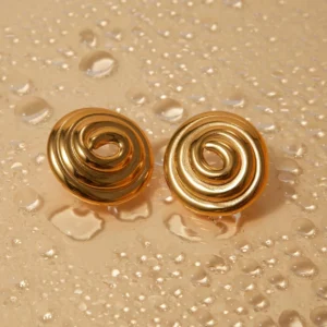 Close-up of 18K gold spiral earrings showing glossy concentric spiral design with water droplets
