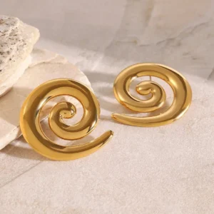 Gold spiral earrings worn styling oblique angle marble surface luxury presentation 18K gold design