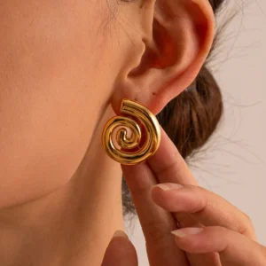 18K gold spiral stud earrings worn on ear - close-up of female model wearing polished gold earring with hand adjusting