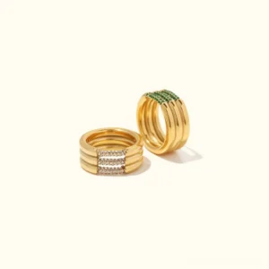18K gold stackable pavé rings flat lay - emerald and diamond simulant variants with neutral background