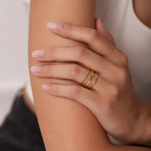 Stacked slim gold rings worn on female hand, close-up side view showcasing minimalist band design