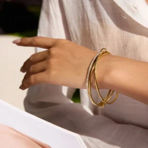 18K gold stacked bracelet worn on wrist side angle view female model poolside casual