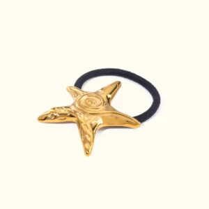 Close-up flat lay of 18k gold starfish hair cuff with polished spiral texture on plain background showing product detail