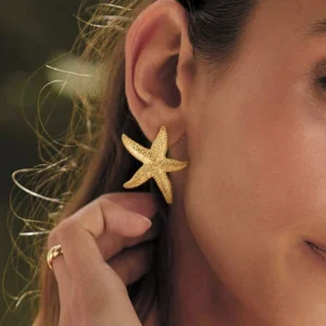 18K gold starfish earring worn on ear close-up side view with model wearing polished gold finish
