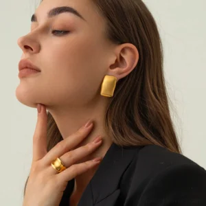 Model wearing 18K gold rectangle stud earrings side profile close-up with black blazer and matching gold ring