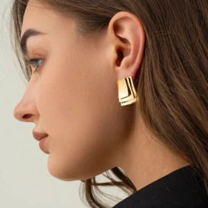 Gold stud earrings worn on model profile close-up modern minimalist ear jewelry styling