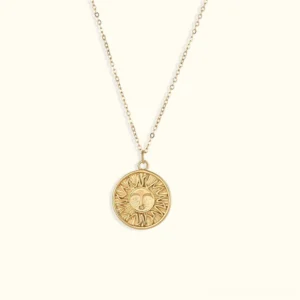 18K gold sun coin pendant necklace front flat lay view - round engraved sun face with delicate cable chain on light background