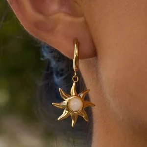 18K gold sun-shaped moonstone drop earrings worn on model ear outdoor setting showcasing gold finish and light-catching moonstone