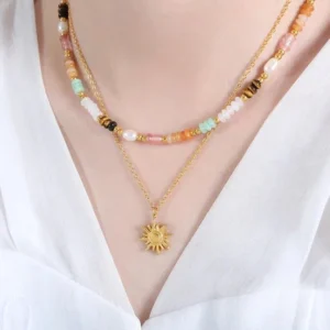 Delicate 18K gold sun necklace worn layered with beaded accents on female model in white blouse