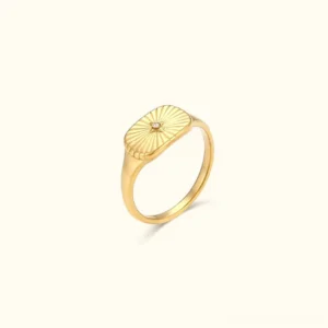 18K gold sunburst signet ring with textured face and central stone accent, shown against neutral background - product photography