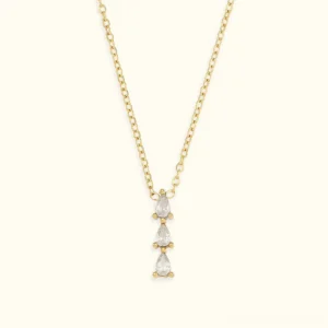 18K gold teardrop diamond simulant pendant necklace flat lay top-down view showcasing three stacked pear-cut clear stones on delicate gold chain