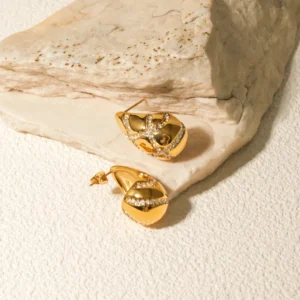 Solid 18K gold teardrop stud earrings polished finish side view on beige stone backdrop