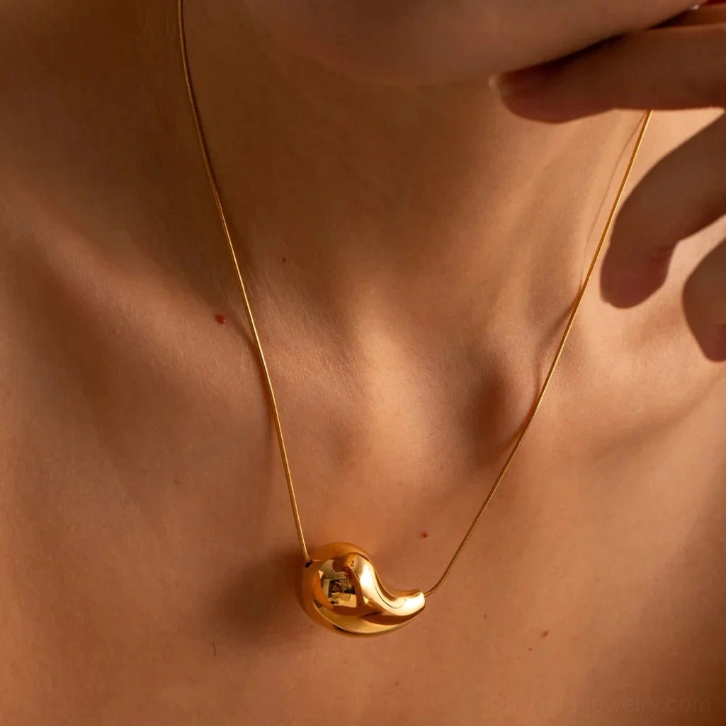 Gold teardrop drop necklace worn by model - overhead angle showing bright polished finish and thin gold chain