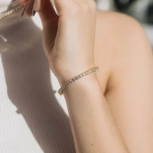 Silver-toned 18K gold tennis bracelet worn on female wrist, close-up side view showing delicate stone setting and band