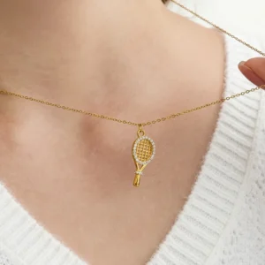 Close-up of 18K gold tennis racket necklace worn on neck, sparkling diamond pendant detail, white knit top styling