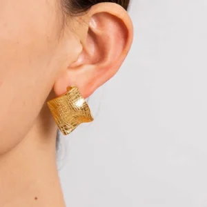 Close-up side view of 18K gold textured earrings worn on earlobe showing crisscross engraved pattern and fit