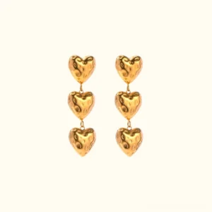 18K gold triple heart drop earrings with hammered texture flat lay on neutral background