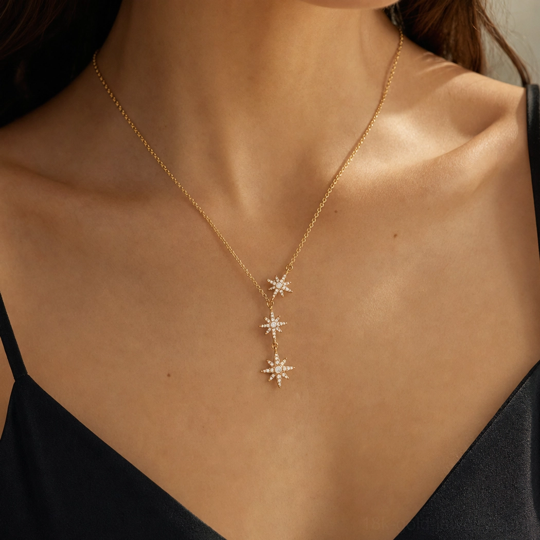 18K gold triple star cascade drop necklace on-body front shot model wearing black camisole showing three descending star pendants