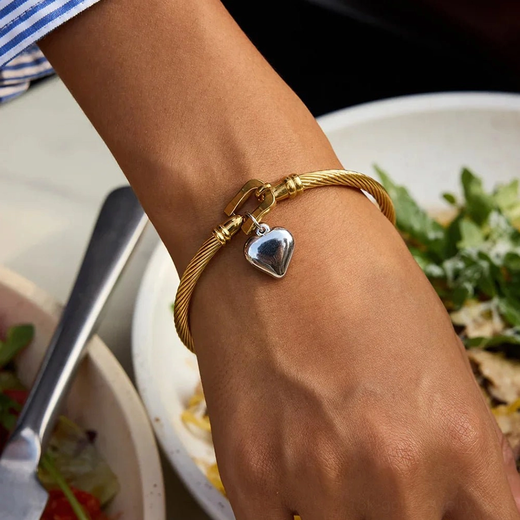 18K gold twisted cable bracelet close-up side view on woman's wrist at dining table, casual daily styling with clear pendant detail