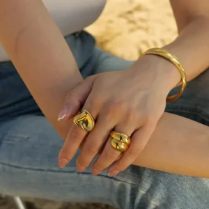 18K gold twisted dome rings on female model hands outdoor sandy scene chunky polished metal dome ring styling inspiration