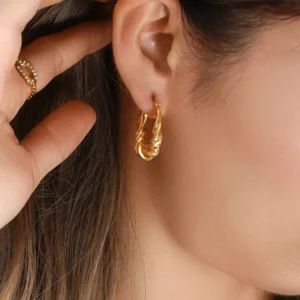 18K gold twisted hoop earrings worn on ear close-up side view showing perfect fit on earlobe with textured metal finish detail