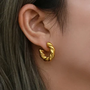 Woman wearing 18K gold twisted hoop earrings close-up on earlobe showing luxury gold jewelry styling