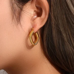 Close-up of 18K gold twisted square hoop earrings worn on ear showing how the earrings fit and the detailed twisted rope pattern in natural light