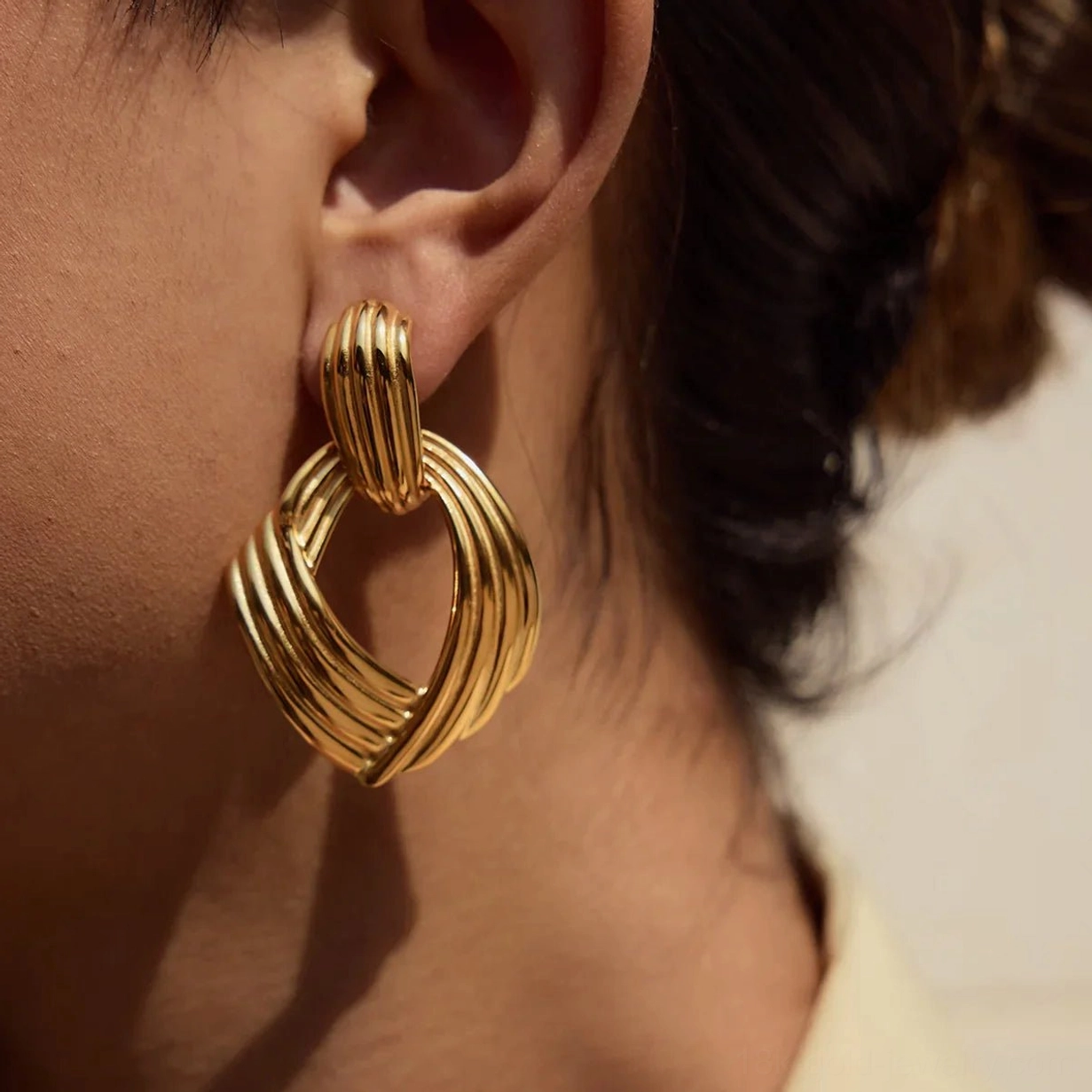 18K gold twisted drop earrings close-up on ear model side view chunky ribbed design polished finish