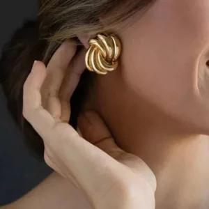 18K gold twisted knot studs worn on female model ear close-up side view showing fit and glossy gold appearance on dark background