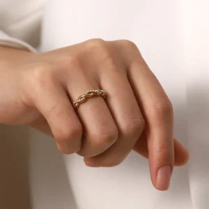 Twisted 18K gold pearl ring on female model hand - close-up detail showing pearl placement and twisted band design