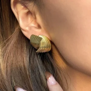 Close-up side view of 18K gold twisted ribbed earring on female earlobe showcasing detailed texture and shine