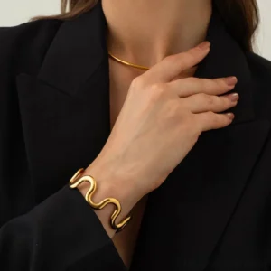 Gold wave bangle and matching choker set worn on model black blazer close-up