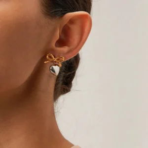 18K gold two-tone heart bow earrings worn on ear close-up side view showing dual-tone metal design and how earrings look when worn