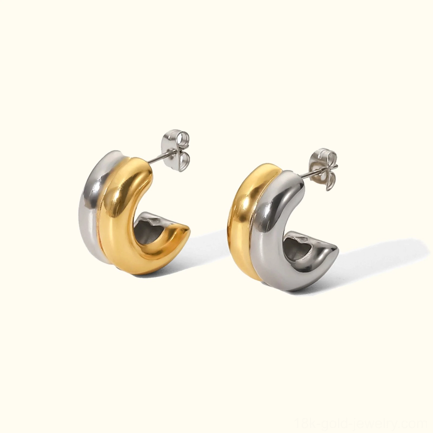 Dual-tone gold and silver chunky hoop earrings, flat lay top view on off-white background showing color contrast