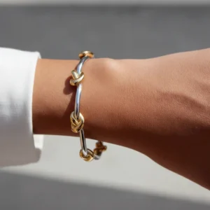 Two-tone gold and silver knotted bangle close-up side wrist shot showing detailed knot decorations