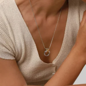 18K gold ring knot necklace worn on model's neck showing how pendant sits on chest with silver chain and gold accent detail