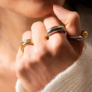 Mixed metal stackable rings worn on female model fingers showing two-tone silver and gold band designs with polished finish