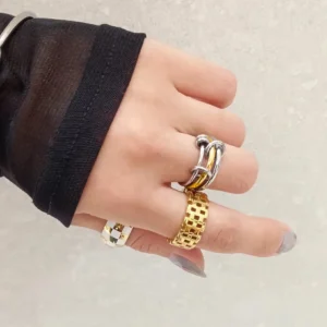 hand model wearing 18K gold two-tone stacked rings on multiple fingers with black sheer sleeve showing layered ring styling versatility