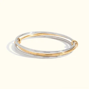 18K gold two-tone stacked bangle bracelet flat lay, polished gold and silver dual-tone design on plain background